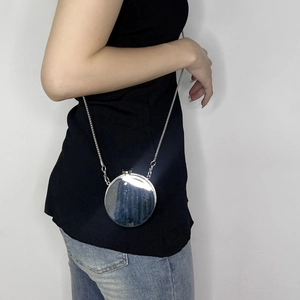 Mini silver round acrylic chain bag with spherical metal strap shown on a model