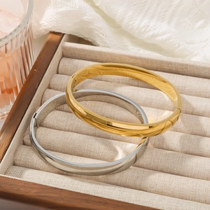 Minimalist geometric gold and silver open bangles set on a velvet jewelry box tray