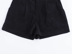 Dettaglio di pantaloncini in velluto a coste nero con vita a pieghe e trama del tessuto