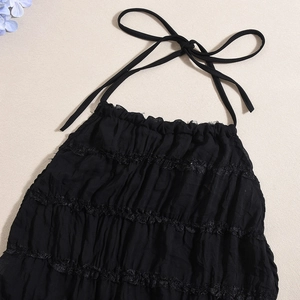 Detailed close-up of a black halter top with ruffled lace edges and pleated texture
