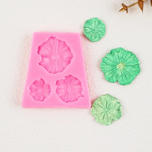 Detailed pink silicone mold for 3D lotus leaf shapes with green finished fondant samples