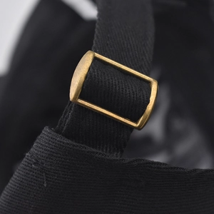 Gros plan sur une casquette en coton noir avec boucle de réglage en métal bronze antique