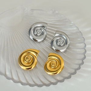 Polished spiral seashell stud earrings in gold and silver finish on a shell tray