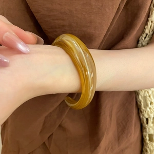 Detail of amber acrylic bangle with smooth glossy finish and marble swirl texture