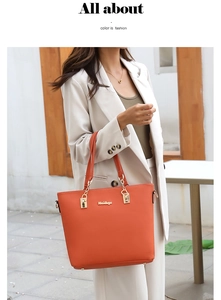 Detail of vibrant orange tote bag with golden chain and leather handle held by model