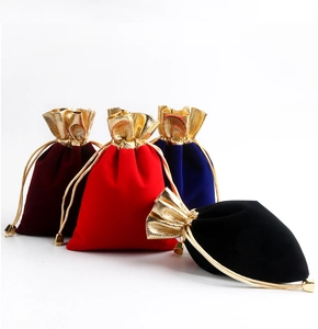 Detail of four velvet drawstring jewelry pouches in red, blue and black with gold trim