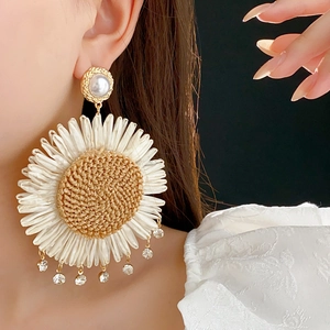 Close-up of bohemian woven sunflower earring with pearl stud and sparkling rhinestone fringe