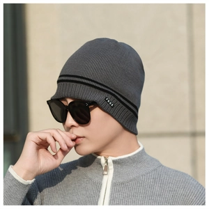 Close-up of dark grey knitted beanie showing fine vertical textures and FBQE logo label
