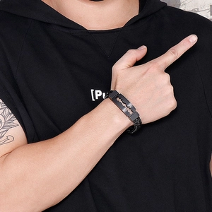 Detail of matte black razor blade pendant on a double-row woven chain bracelet