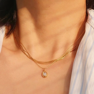 Three-layer gold titanium steel necklace with an oval zircon pendant on a model