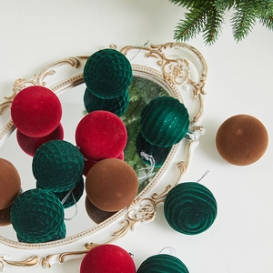 Flocked Christmas ball ornaments in red, green, and brown displayed on a mirror tray