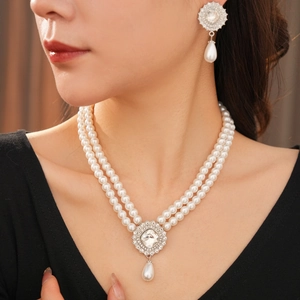 Close-up of double-layer pearl necklace and teardrop earrings set with cubic zirconia