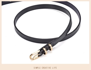 Detailed close-up of a slim black leather belt featuring a polished golden D-ring buckle