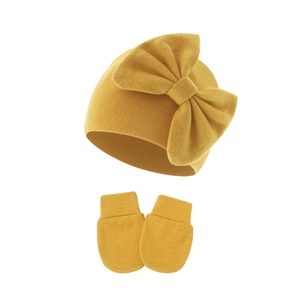 Detail view of mustard yellow knit baby hat with bow and matching anti-scratch mittens