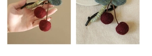 Detail of red knitted cherry hair claw clip with green stem on high-quality black plastic