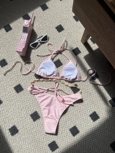 Flat lay of pink triangle bikini with shell chain detail and Y2K aesthetic accessories