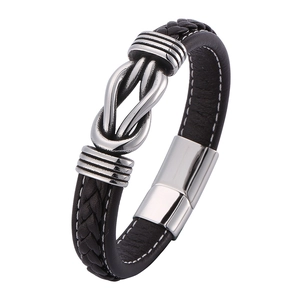 Close-up of black braided leather bracelet with white stitching and silver metal knot