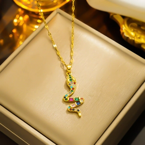 Gold snake necklace with colorful zircon pendant on a beige jewelry box for a luxury look