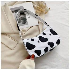 Detailed view of chic cow print underarm bag with zipper closure on a beige blazer