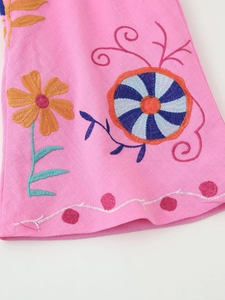 Macro detail of colorful floral and geometric embroidery on pink cotton linen fabric