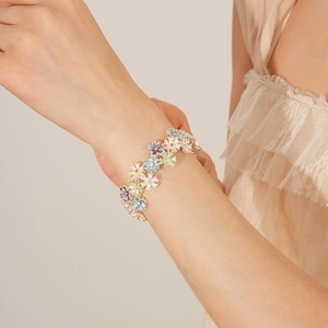 Detail view of colorful enamel daisy flower bracelet worn on wrist with silver base