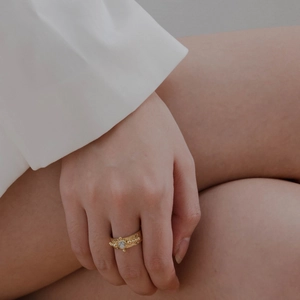 Detail of 18K gold plated ring featuring a white round gemstone and golden bead accents