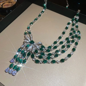 Macro view of crystal bowknot necklace featuring green gemstones and cascading tassels