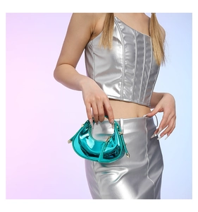 Teal shiny patent leather mini crescent bag with gold hardware shown by model