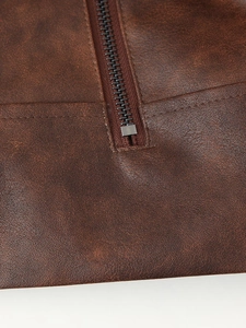 Gros plan sur la texture du similicuir marron et le zip métallique de la veste