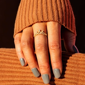 Macro shot of a minimalist gold crown ring with zircons worn on a finger