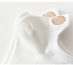 Close-up of white cotton low-cut socks with cute brown smiley face embroidery details