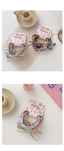 Detailed view of elastic hair ties in Morandi colors with minimal bow accents on card