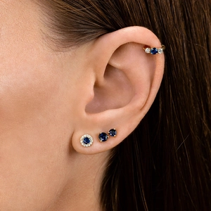 Detail of blue zircon stud earrings and gold ear cuff set on a model's ear
