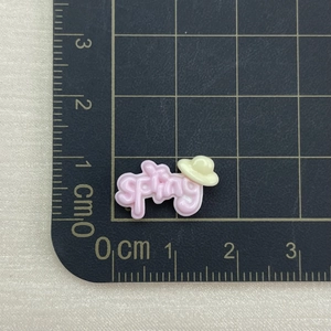 Close-up of pink resin cloud charm with spring text on a scale for size measurement
