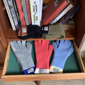 Five pairs of assorted color block thick knitted gloves in a cozy wooden drawer