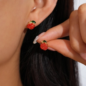 Detailed close-up of a red apple stud earring with sparkling crystals and green leaf