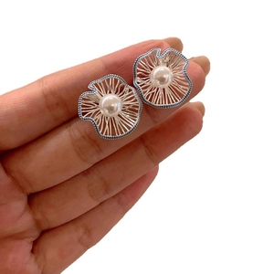 Elegant silver wire hollow flower earrings with white pearl center on a white background