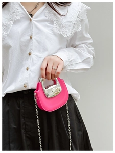 Pink saddle handbag with silver chain and handle shown in a minimalist shoulder carry style