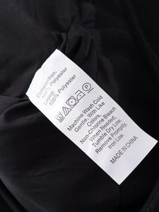 Care label showing 100% polyester composition and washing instructions on a black jacket