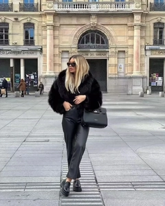 Street style d'une femme portant une veste noire en fausse fourrure et un pantalon en cuir