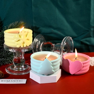 Dettaglio di vasetti per candele in ceramica colorata con rilievi di alberi e fiocchi di neve