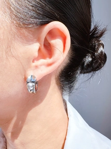Close-up of minimalist silver hoop earring with grey pearl worn by a model