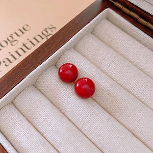 Macro shot of minimalist round red agate stud earrings on premium velvet jewelry box