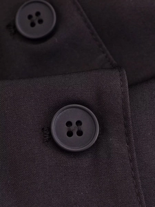 Detail of elegant black blazer dress featuring textured fabric and classic four-hole buttons