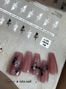 Vista macro di adesivi per unghie con rose in rilievo e motivi floreali bianco e nero