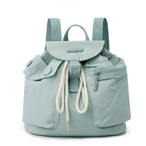 Detail of mint green nylon backpack showing large pockets and adjustable drawstring closure