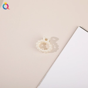 Close-up of elegant small hair claw with white faux pearls and gold metal clip