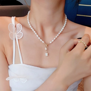 Elegant freshwater pearl necklace with rose pendant on a model in a minimalist style