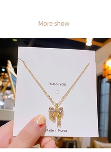 Gros plan d'un collier pendentif nœud doré serti de cristaux blancs sur une carte
