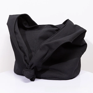 Close-up of the knotted strap detail on a black minimalist canvas hobo shoulder bag